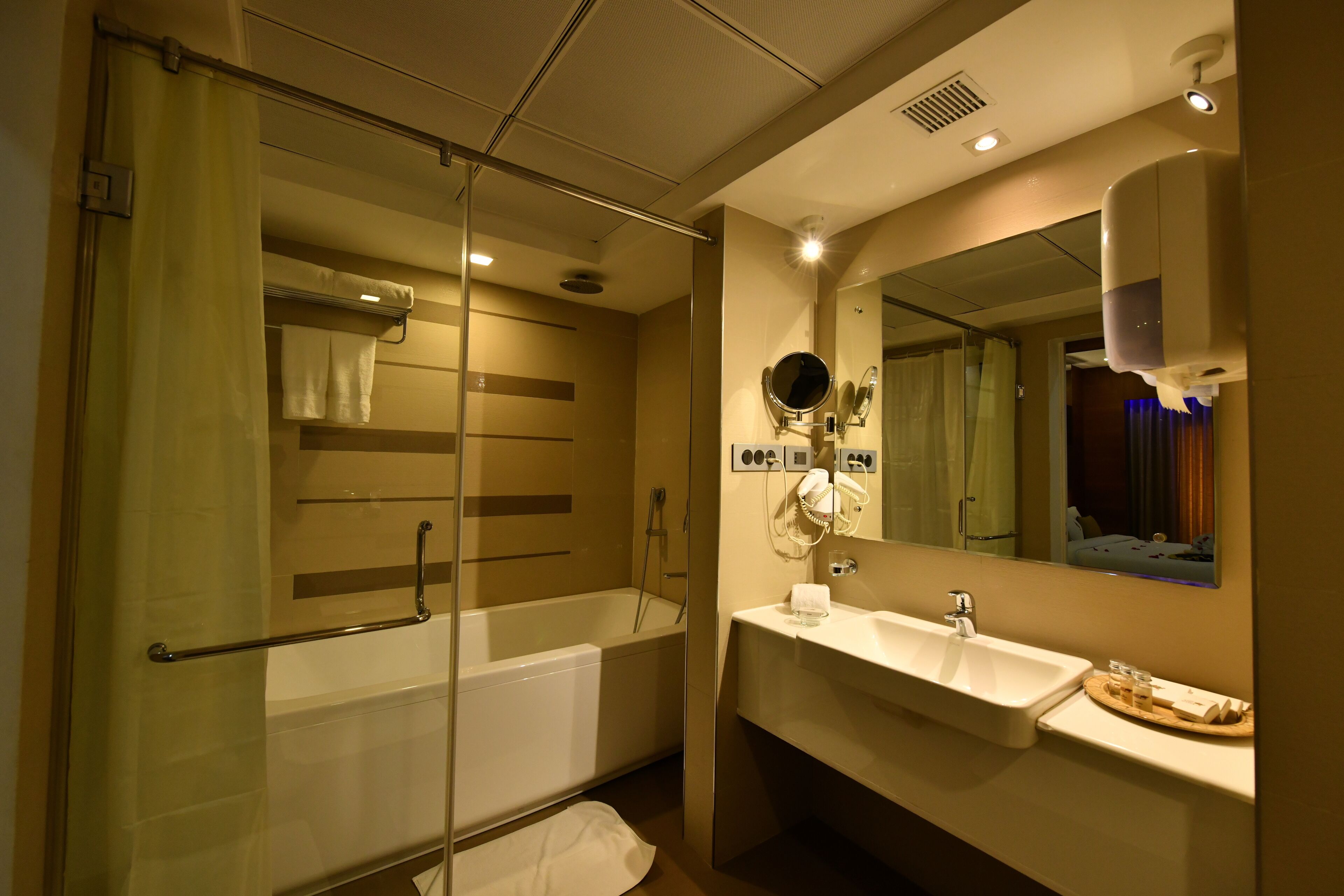 A modern bathroom with a glass-enclosed shower, a white sink, and a large mirror.
