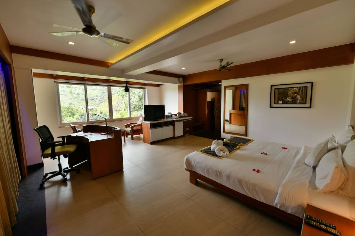 A hotel room with a bed, desk, chair, and a TV.