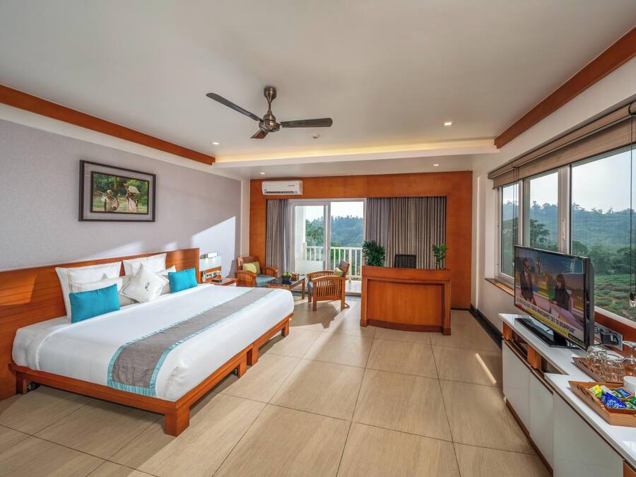 Habitación de hotel con cama, escritorio, televisión y balcón con vistas.