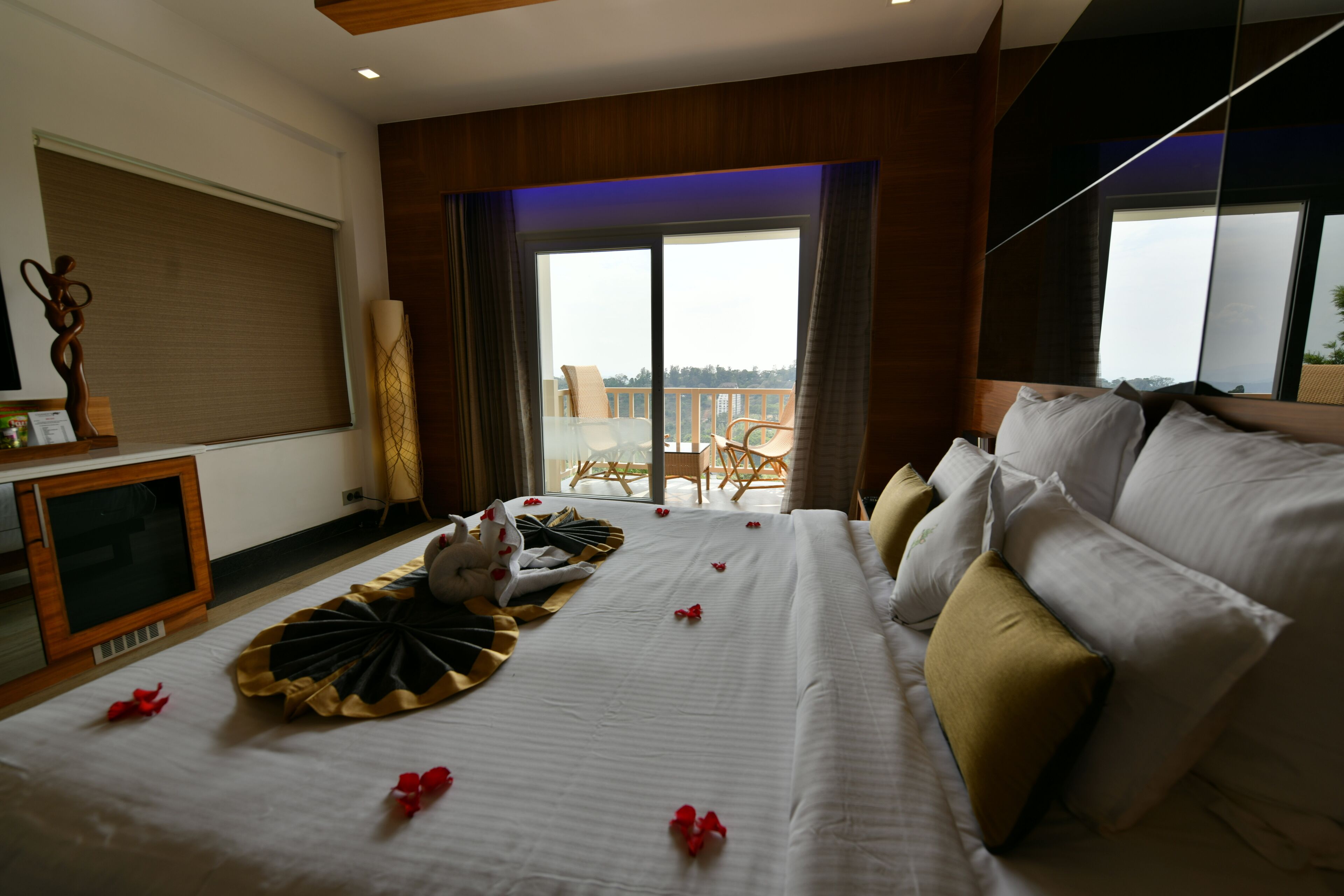 A hotel room with a large bed, a television, and a balcony with a view.