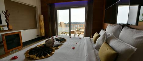 A hotel room with a large bed, a television, and a balcony with a view.