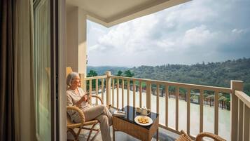 A balcony with a view of a hilly landscape, wicker furniture, and a table with a plate of cookies.