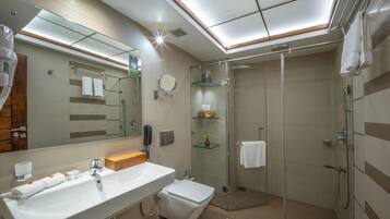 Un baño moderno con un espejo grande, un lavabo, un inodoro, una ducha y cabina de ducha con paredes de vidrio.