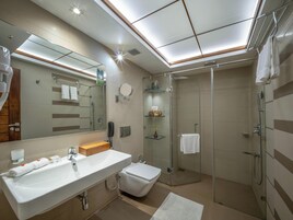 Un baño moderno con un espejo grande, un lavabo, un inodoro, una ducha y cabina de ducha con paredes de vidrio.