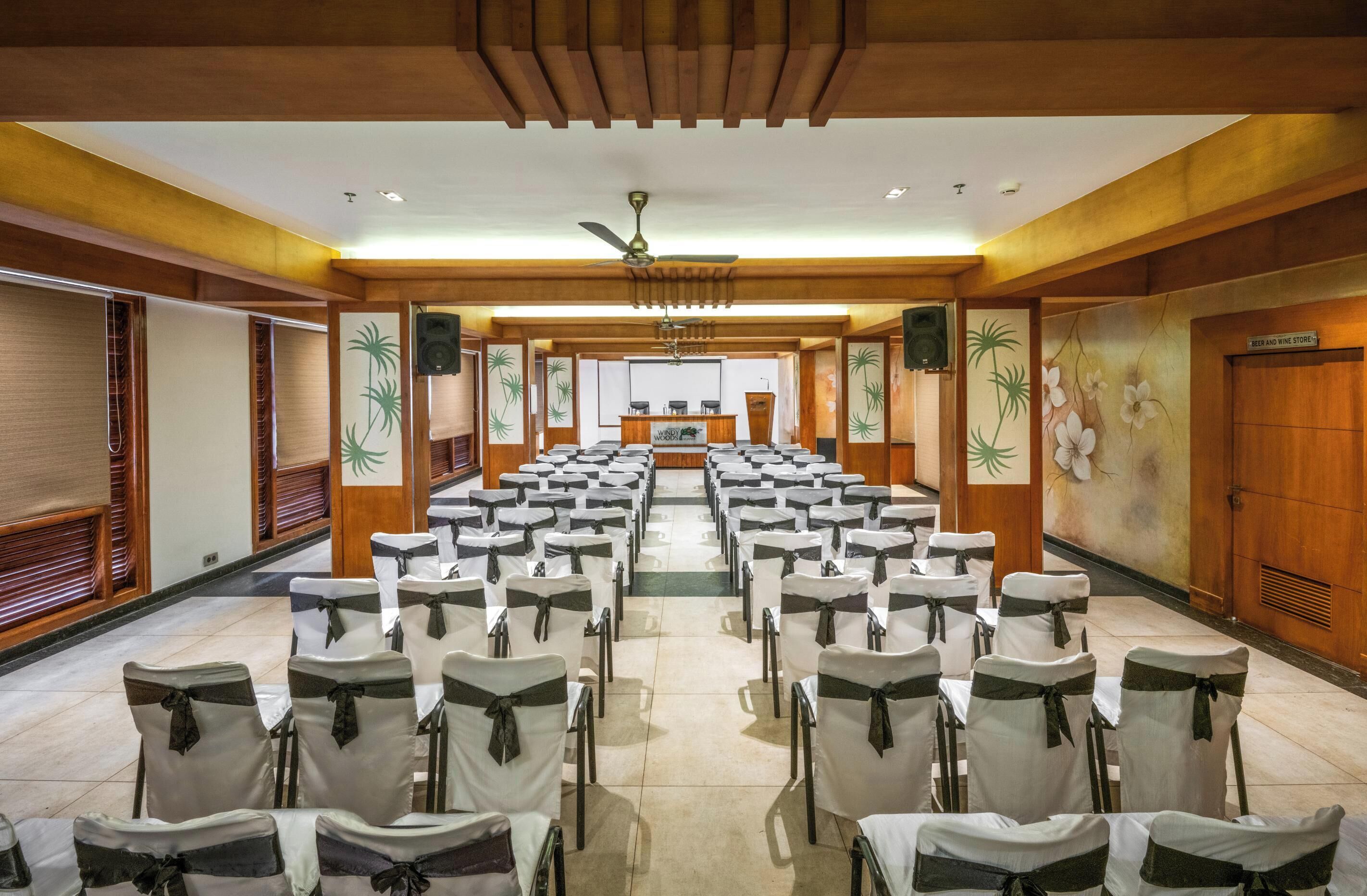 A conference room with rows of chairs, a podium, and a ceiling fan.
