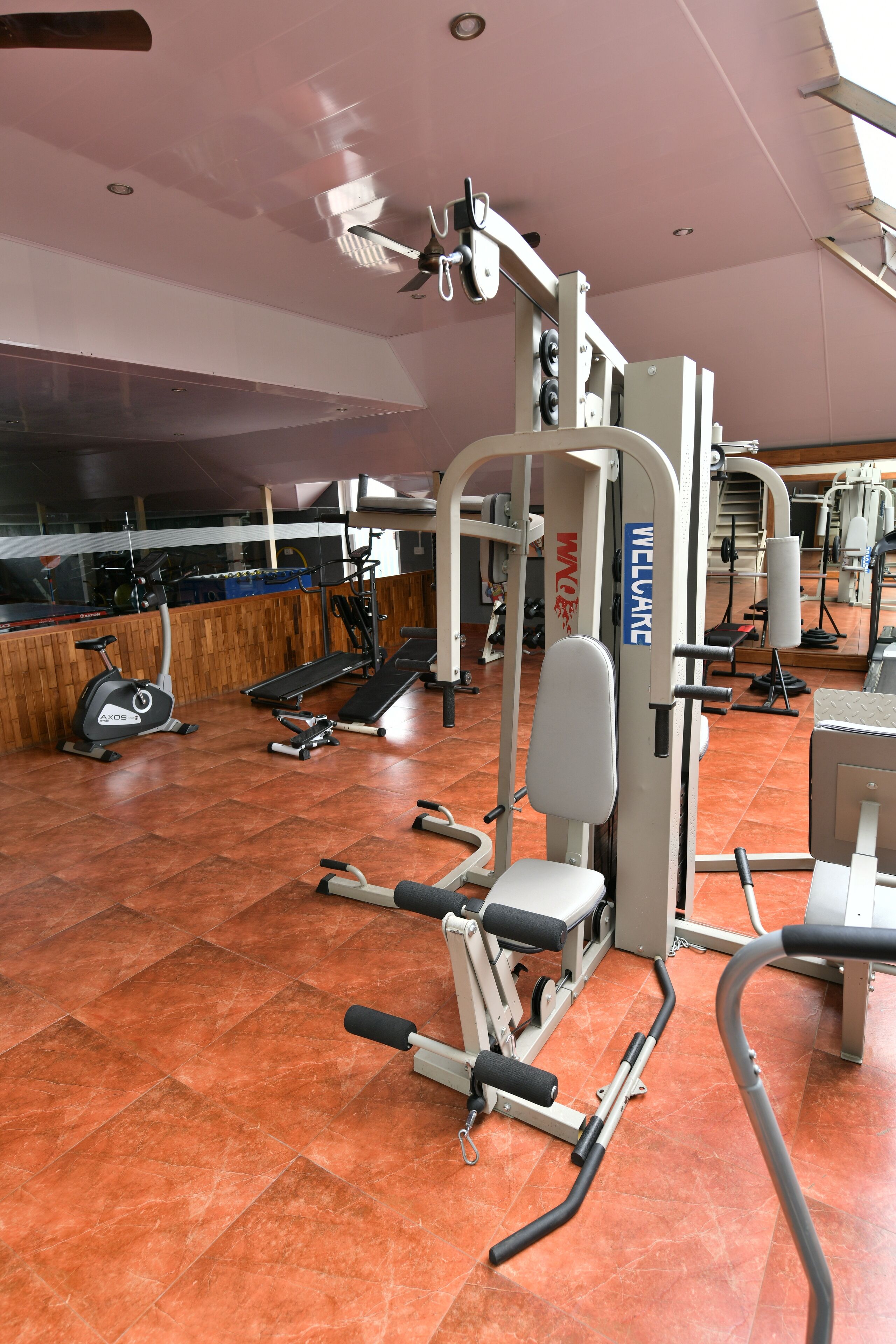 A gym with various exercise equipment, a wooden wall, and a tiled floor.