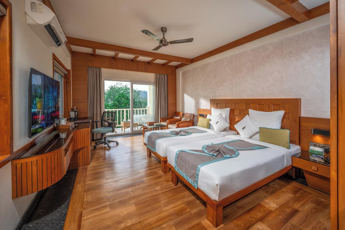 A hotel room with a wooden ceiling, two beds, a desk, a chair, a TV, and a balcony.