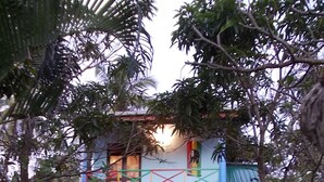 A two-story building with a tiled roof, a balcony, and a front door.