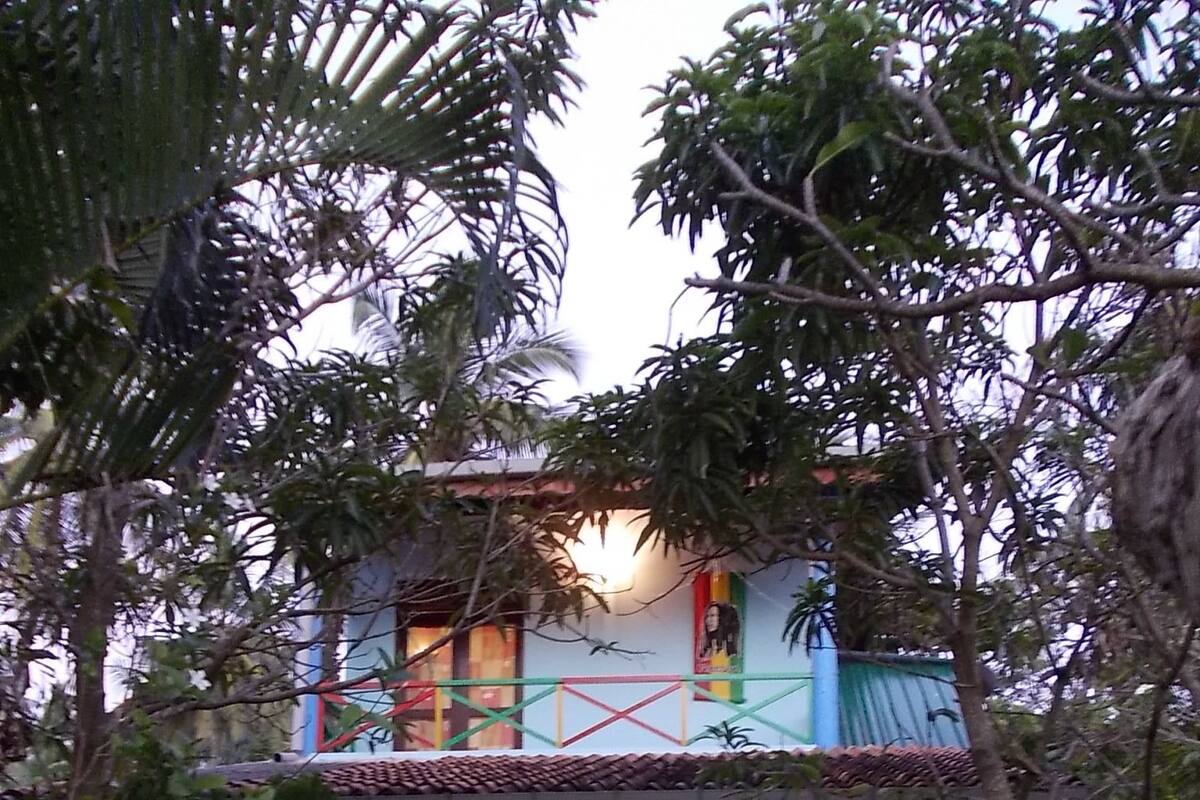 A two-story building with a tiled roof, a balcony, and a front door.