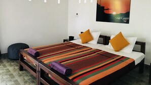 A hotel room with a bed, a nightstand, a wall-mounted air conditioner, and a painting of a sunset.