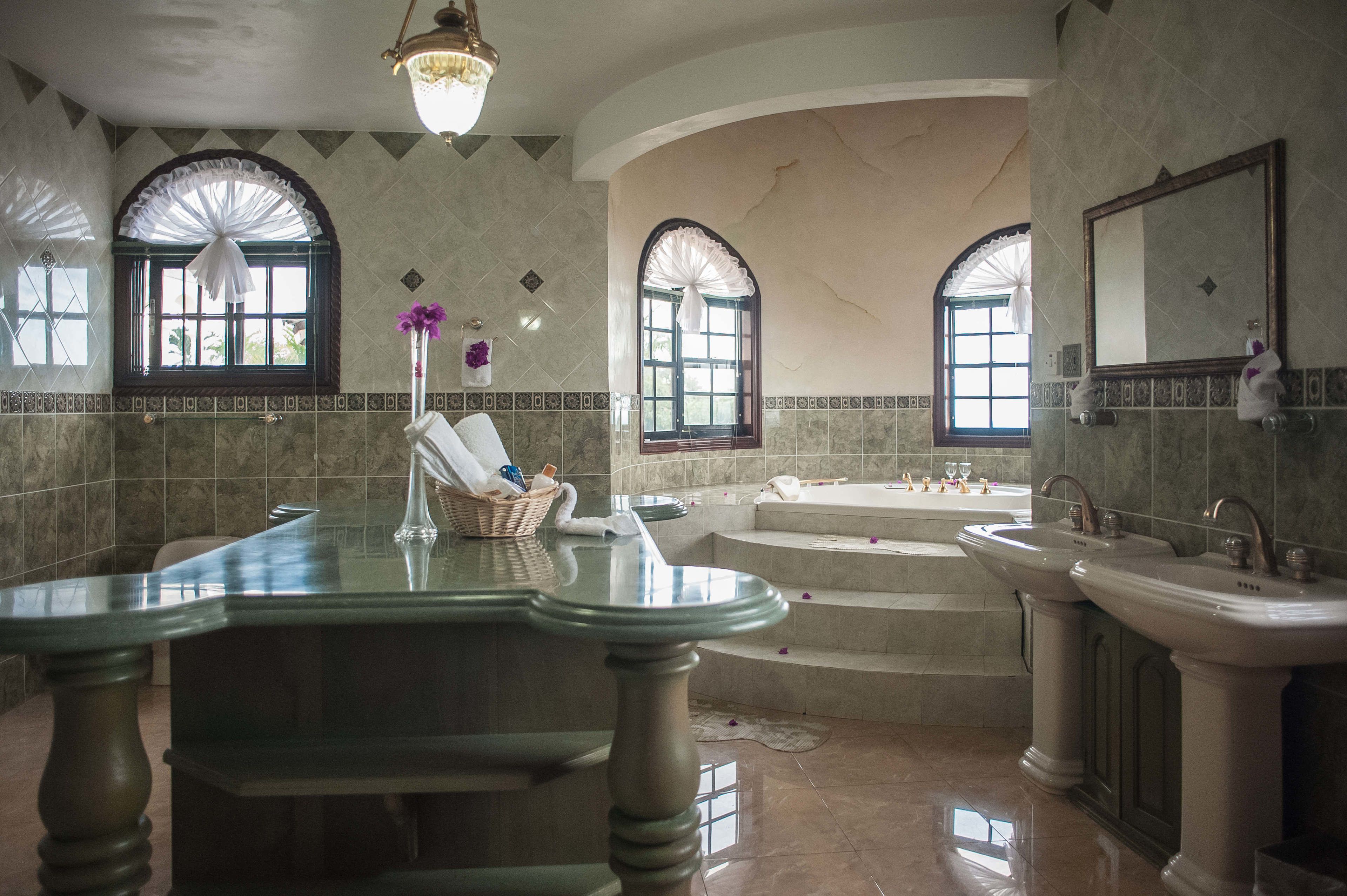 A spacious bathroom with a large bathtub, two sinks, and a vanity.