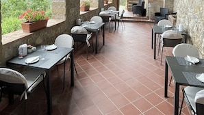 An outdoor patio with stone arches, terracotta flooring, and tables set for dining. - Agriturismo Tenuta di Montemassi La Fattoria (Roccastrada)