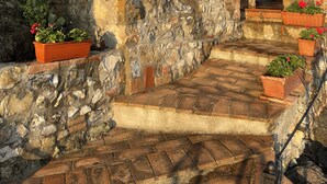 A stone staircase leading to an arched doorway, surrounded by stone walls and potted plants. - Agriturismo Tenuta di Montemassi La Fattoria (Roccastrada)