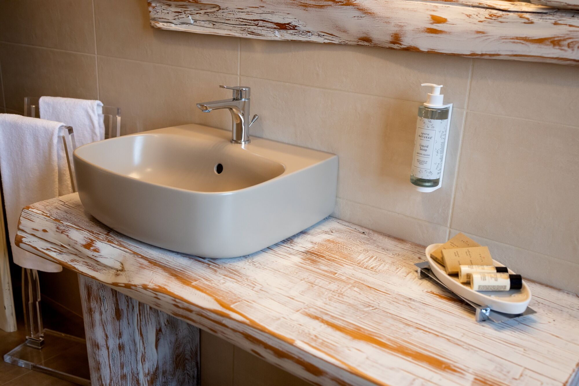 Een badkamer met een witte wasbak, een zeepdispenser en een zeepbakje.