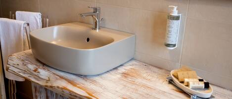 Een badkamer met een witte wasbak, een zeepdispenser en een zeepbakje.