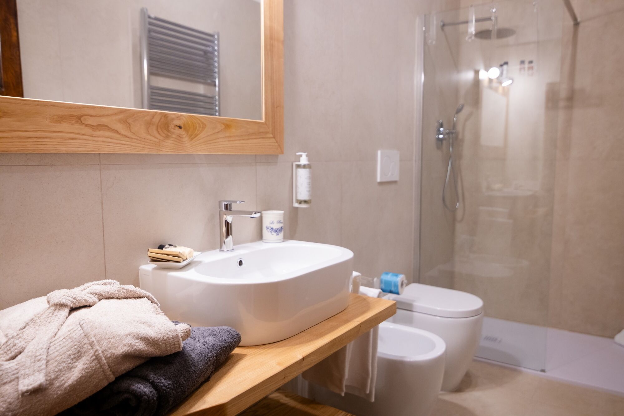 Un bagno con un mobile bagno in legno, un lavandino, un WC e un box doccia.