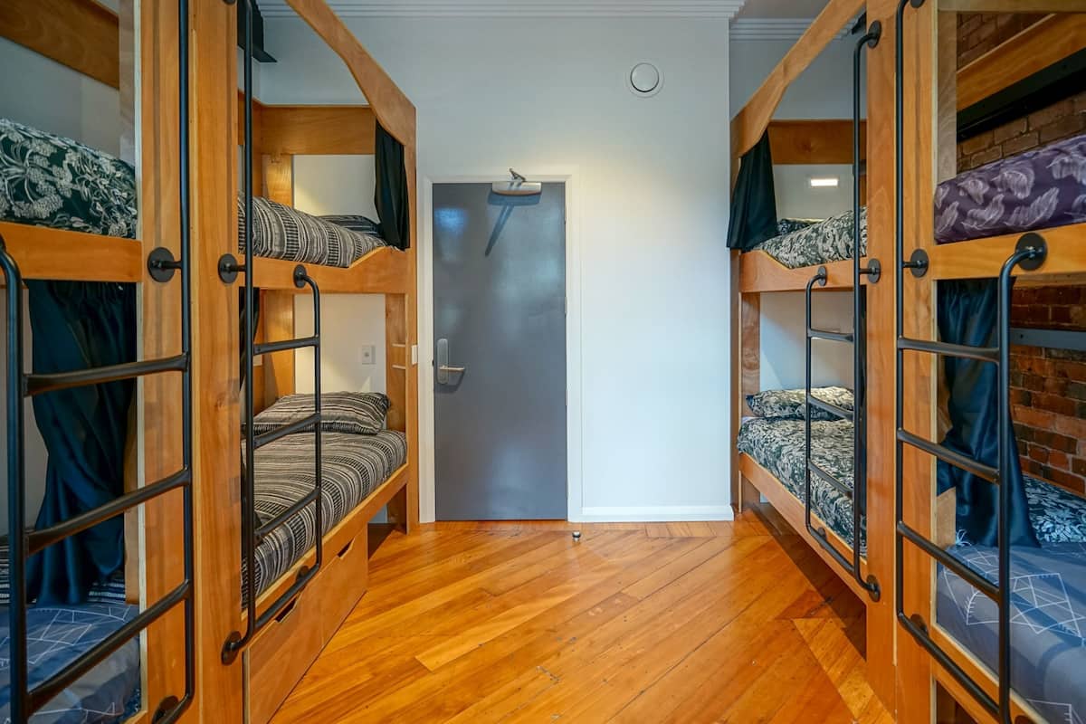 A room with two bunk beds, a wooden floor, and a door.