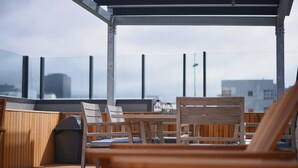 A rooftop terrace with wooden furniture and a glass enclosure. - The Marion Hostel (Wellington)