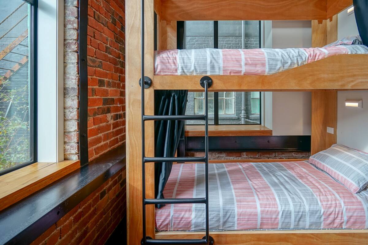 A bunk bed with a ladder, wooden headboard, and striped bedding.