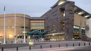 A modern building with a curved facade, a prominent entrance with a blue awning, and a large circular structure to the left. - The Marion Hostel (Wellington)