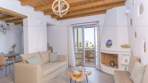 A spacious living area with a wooden ceiling, a sofa, a coffee table, and a fireplace. - Salinus Villas (Naxos)