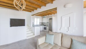 A modern interior with a wooden ceiling, a kitchen area, and a living space with a sofa and a flat-screen TV. - Salinus Villas (Naxos)