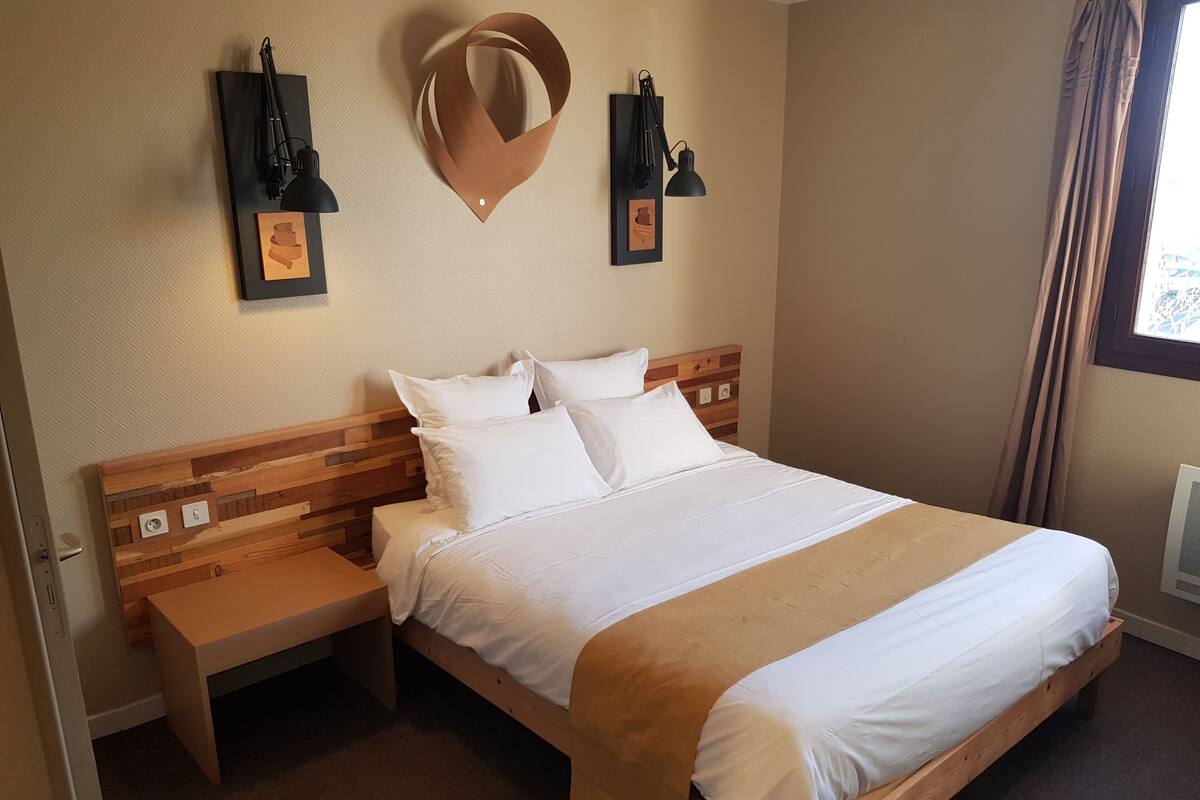 A neatly made bed with white linens, a wooden headboard, and a bedside table with a lamp.