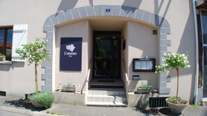 A hotel entrance with a sign reading "L'atelier hotel" and a number "5" above the door. There are potted plants on either side of the entrance. - Résidence l'Atelier (Ennezat)