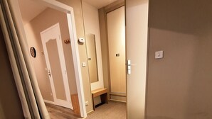A hotel room with a bed, a bench, and a door leading to another room. - Résidence l'Atelier (Ennezat)