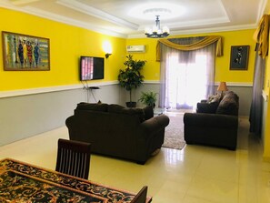 A living room with a sofa set, a dining table, a TV, and a potted plant. - Montgomery Brothers estate (Kenyayai)