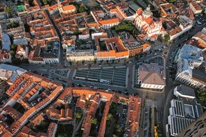 An aerial view of a city with a mix of historical and modern buildings, a central square, and a prominent church with a dome.