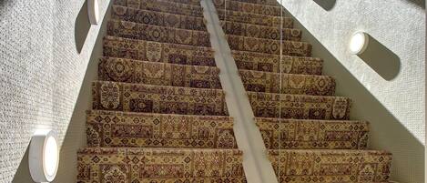 Una escalera con alfombra estampada y apliques de pared.