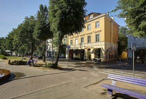 Un immeuble avec un café au rez-de-chaussée, un trottoir pavé et un banc.