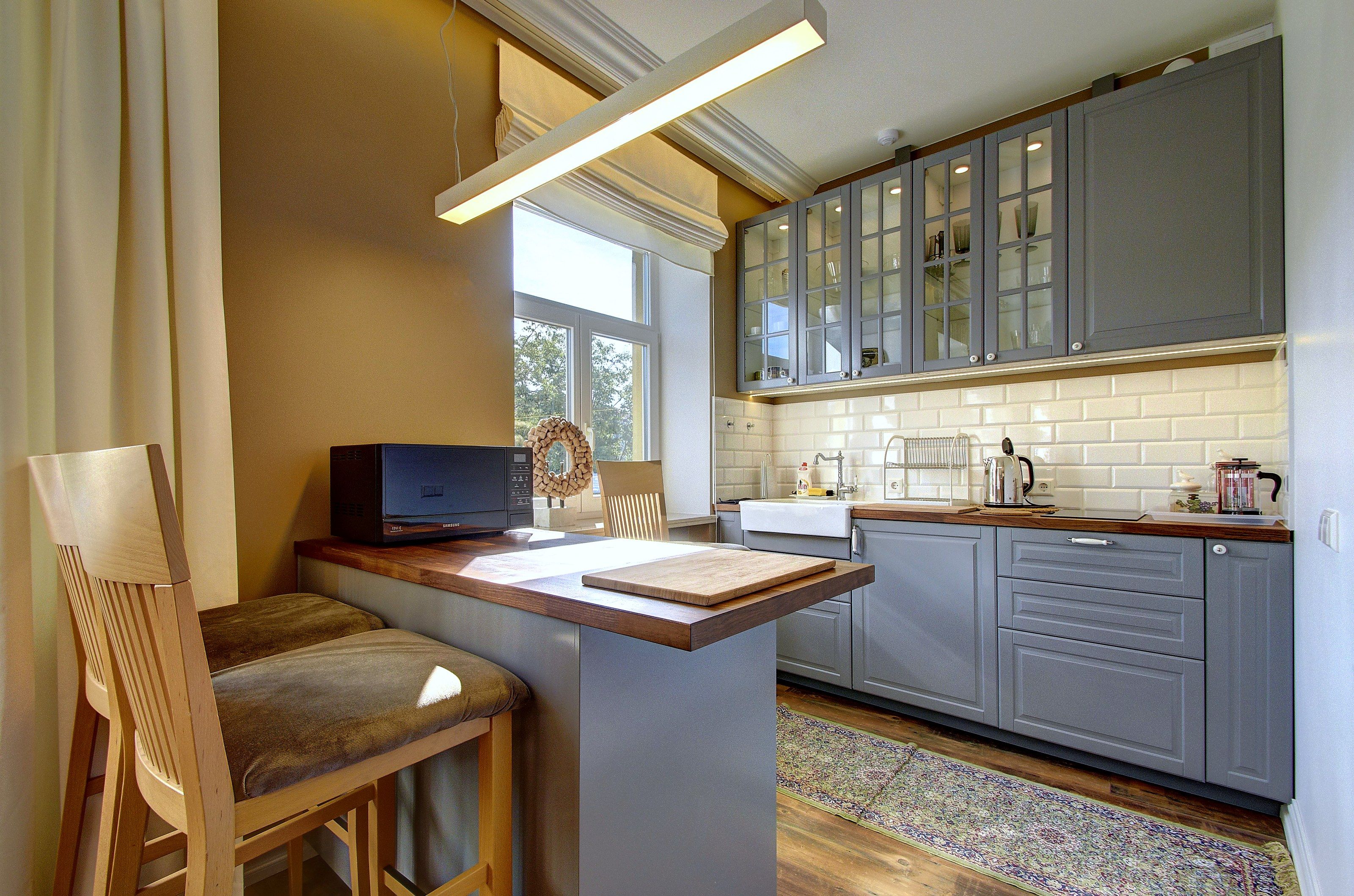 A kitchen with a wooden island, grey cabinets, a window, and a view of the outdoors.