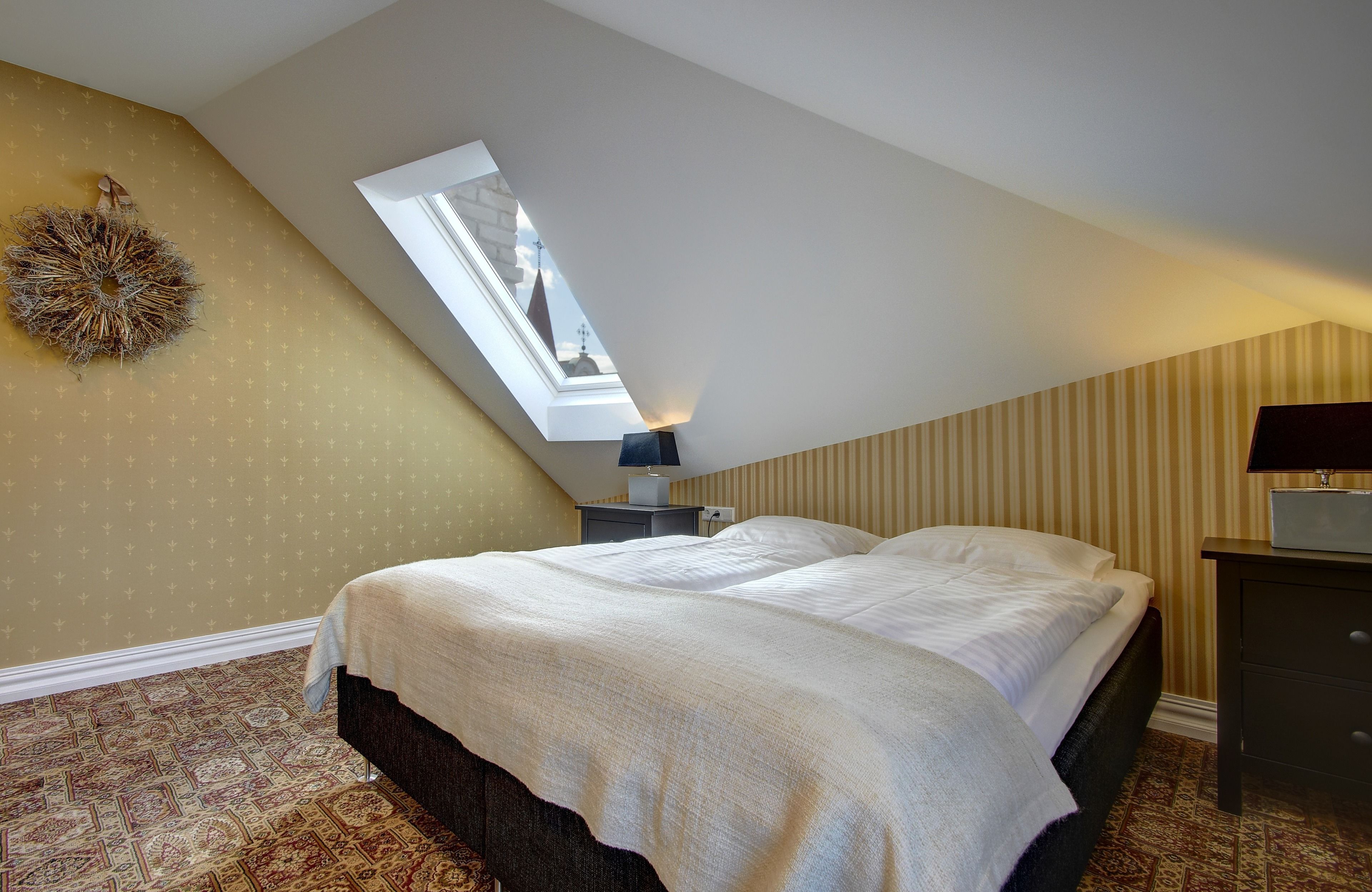 A bedroom with a skylight, a bed, a nightstand, and a dresser.