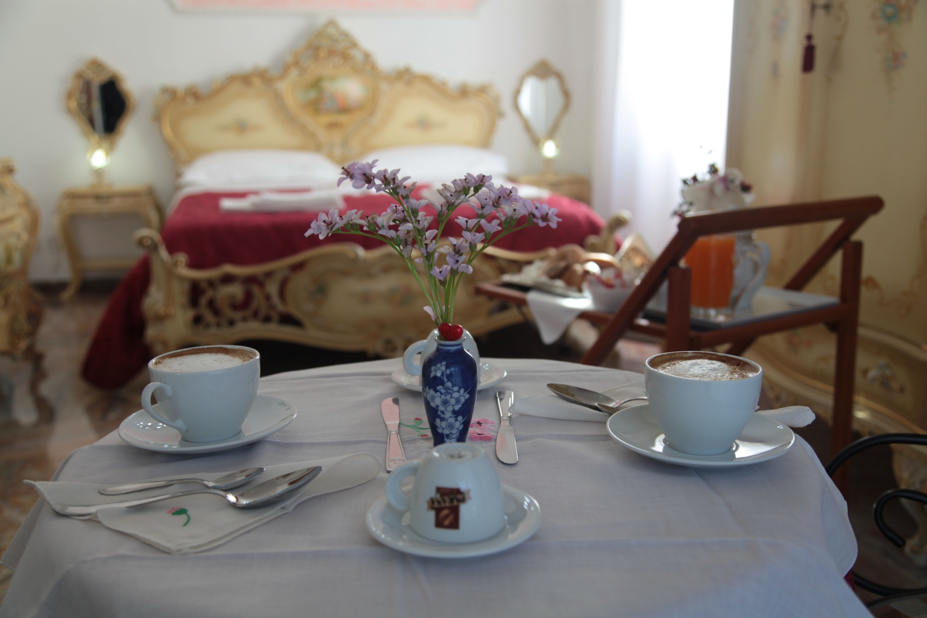 A dining table set with two cups of coffee, a vase with flowers, and a small decorative item.