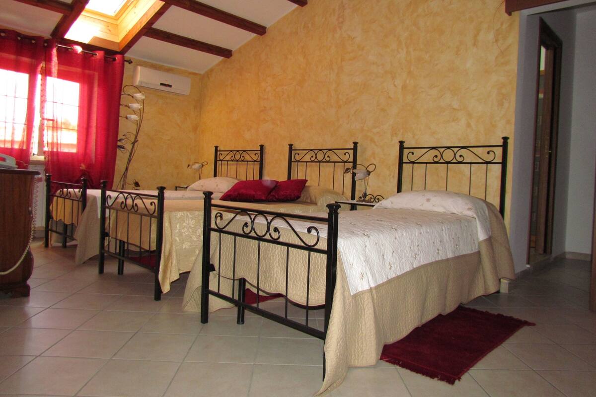 A bedroom with two beds, a wooden ceiling, and a red rug.