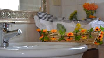 Un lavabo con rubinetteria cromata, uno specchio sopra e un portaserviti con asciugamani piegati.