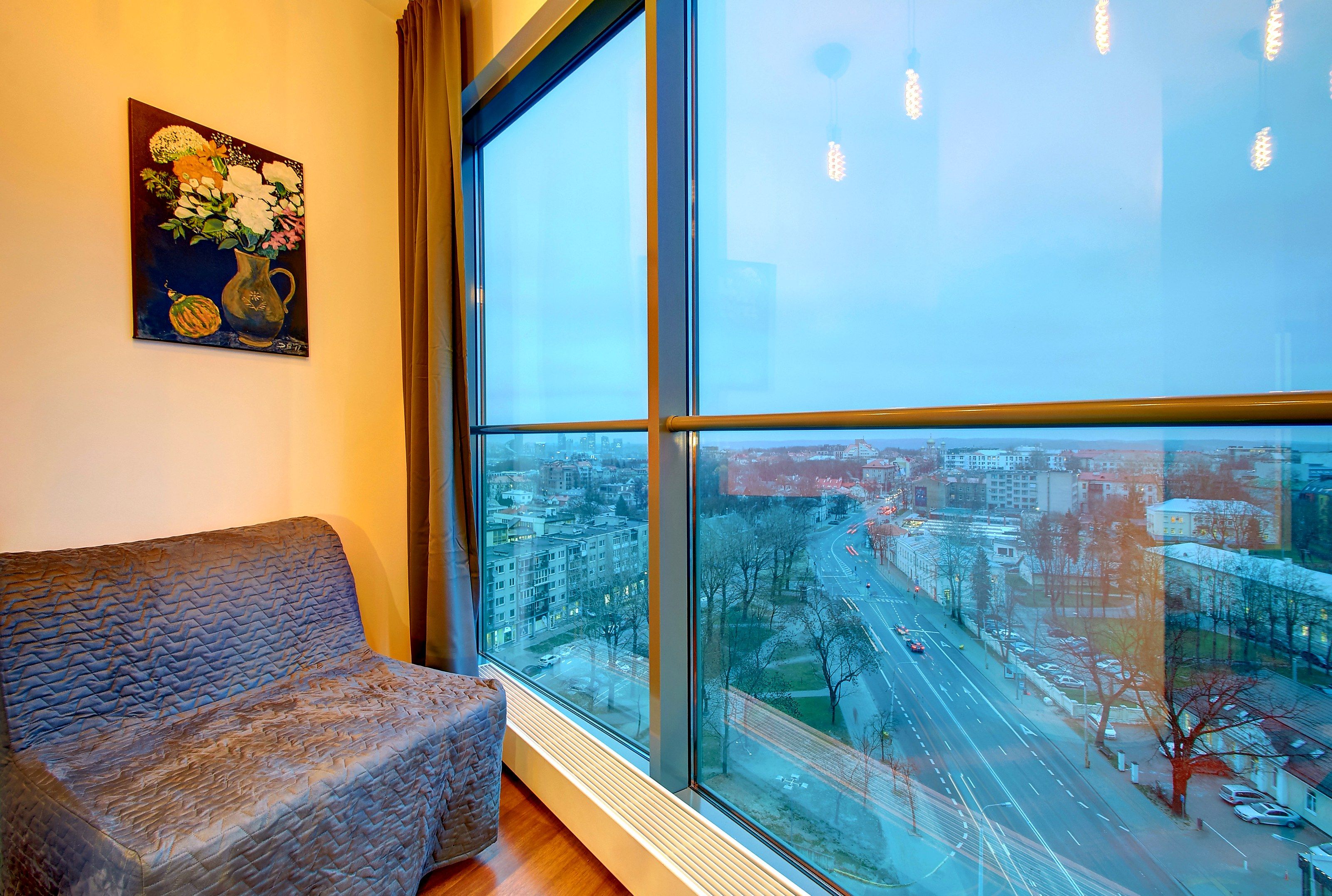 Ein Zimmer mit einem großen Fenster, einer gepolsterten Sitzbank und einem Gemälde an der Wand.
