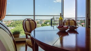 A dining table with chairs, a bottle of wine, and a bowl of fruit. - Helios City Vilnius Apartments (Vilnius)