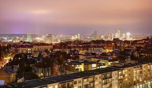A cityscape at night with illuminated buildings and a dense residential area in the foreground. - Helios City Vilnius Apartments (Vilnius)