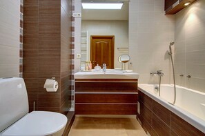 A modern bathroom with a toilet, sink, and bathtub. - Helios City Vilnius Apartments (Vilnius)