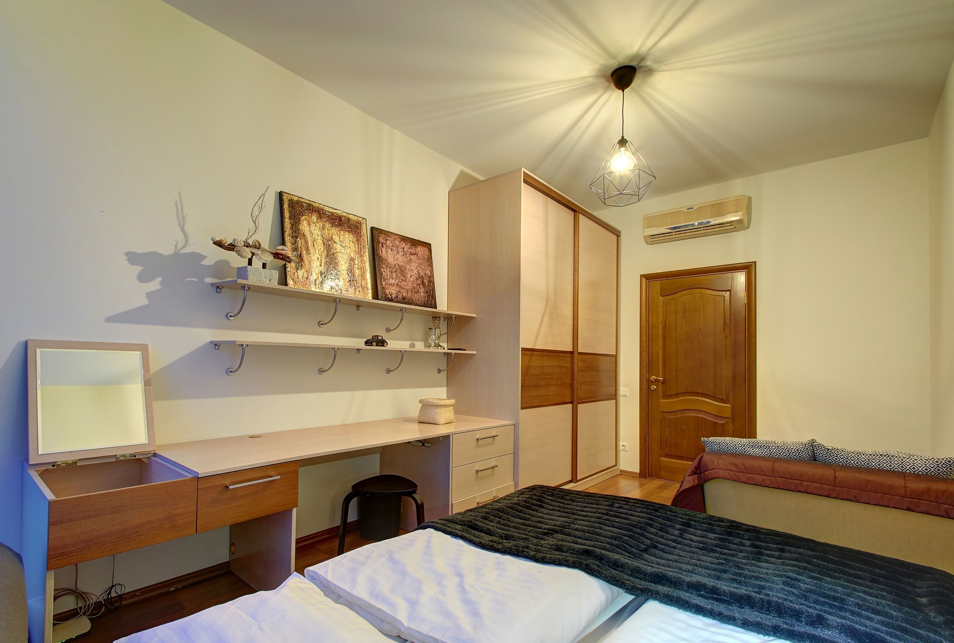 Un dormitorio con cama, escritorio con silla, armario y mesita de noche.