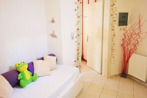 A bedroom with a bed, a green frog toy, and a wall with decorative elements.
