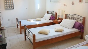 Ein Zimmer mit zwei Holzbetten, einem kleinen Tisch und einem Regal mit Dekoration.