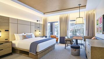 A modern hotel room with a large bed, a desk, and a view of a snowy landscape.