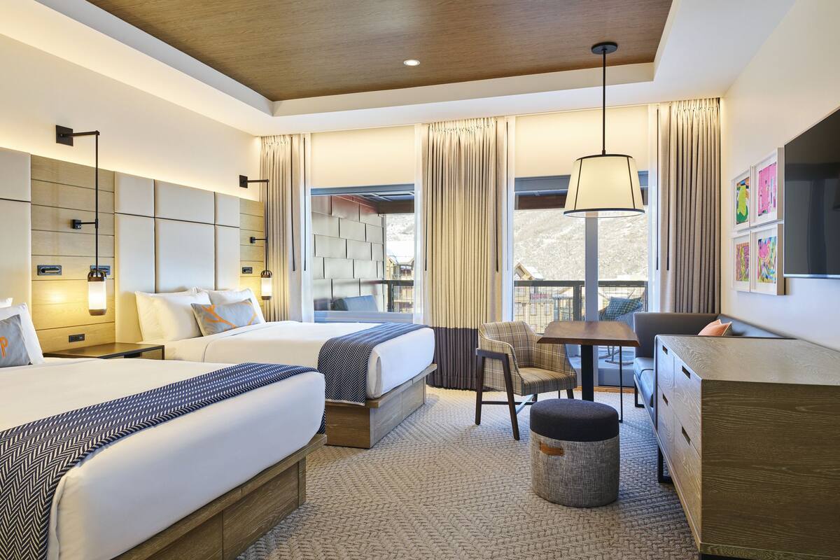 Une chambre d’hôtel avec deux lits, un bureau, une chaise et une petite table.