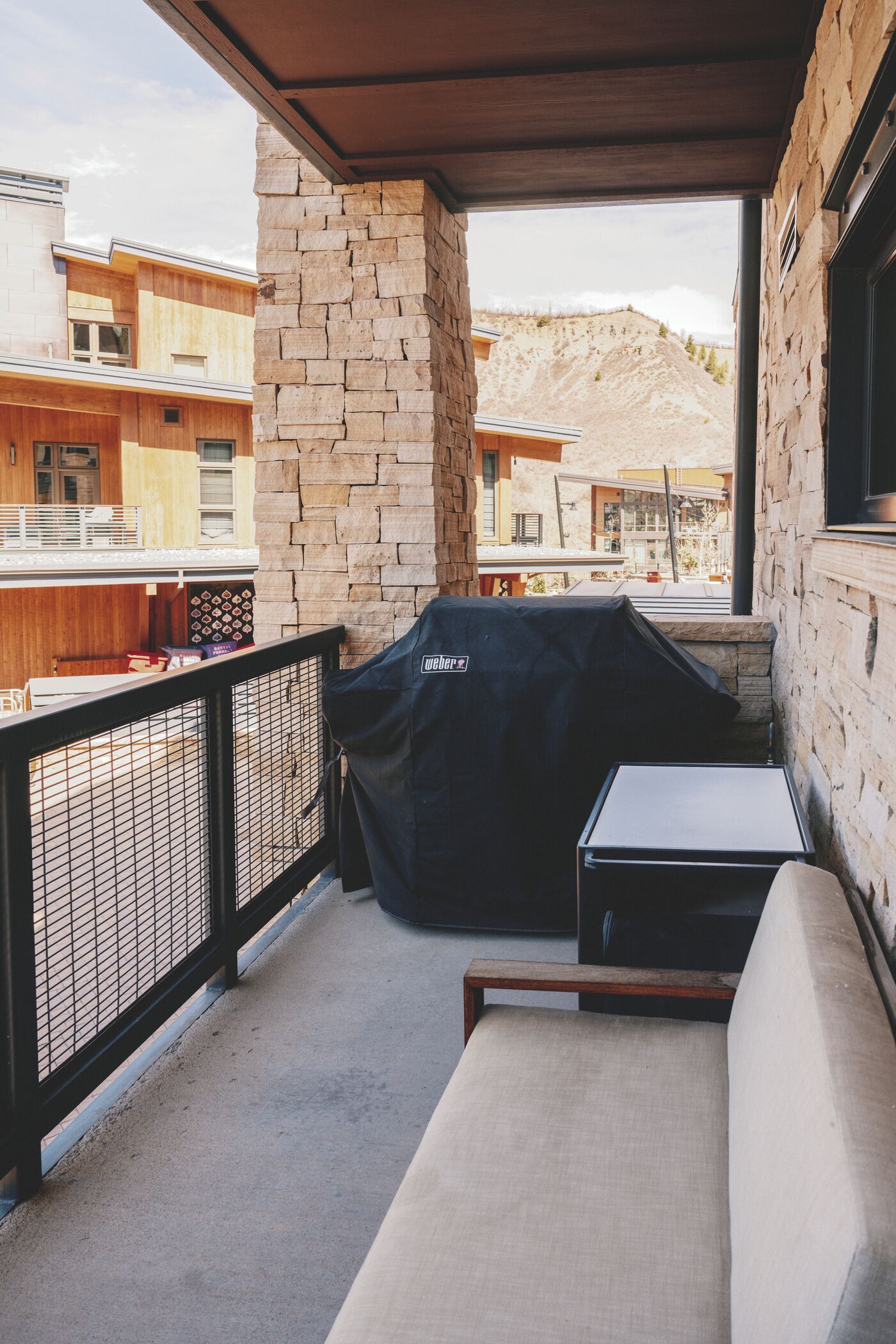 Ein Balkon mit Steinmauer, Grill, Sofa und Tisch.