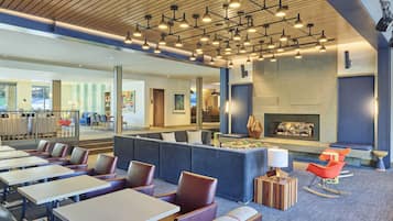 A modern lounge area with seating, tables, and a fireplace.
