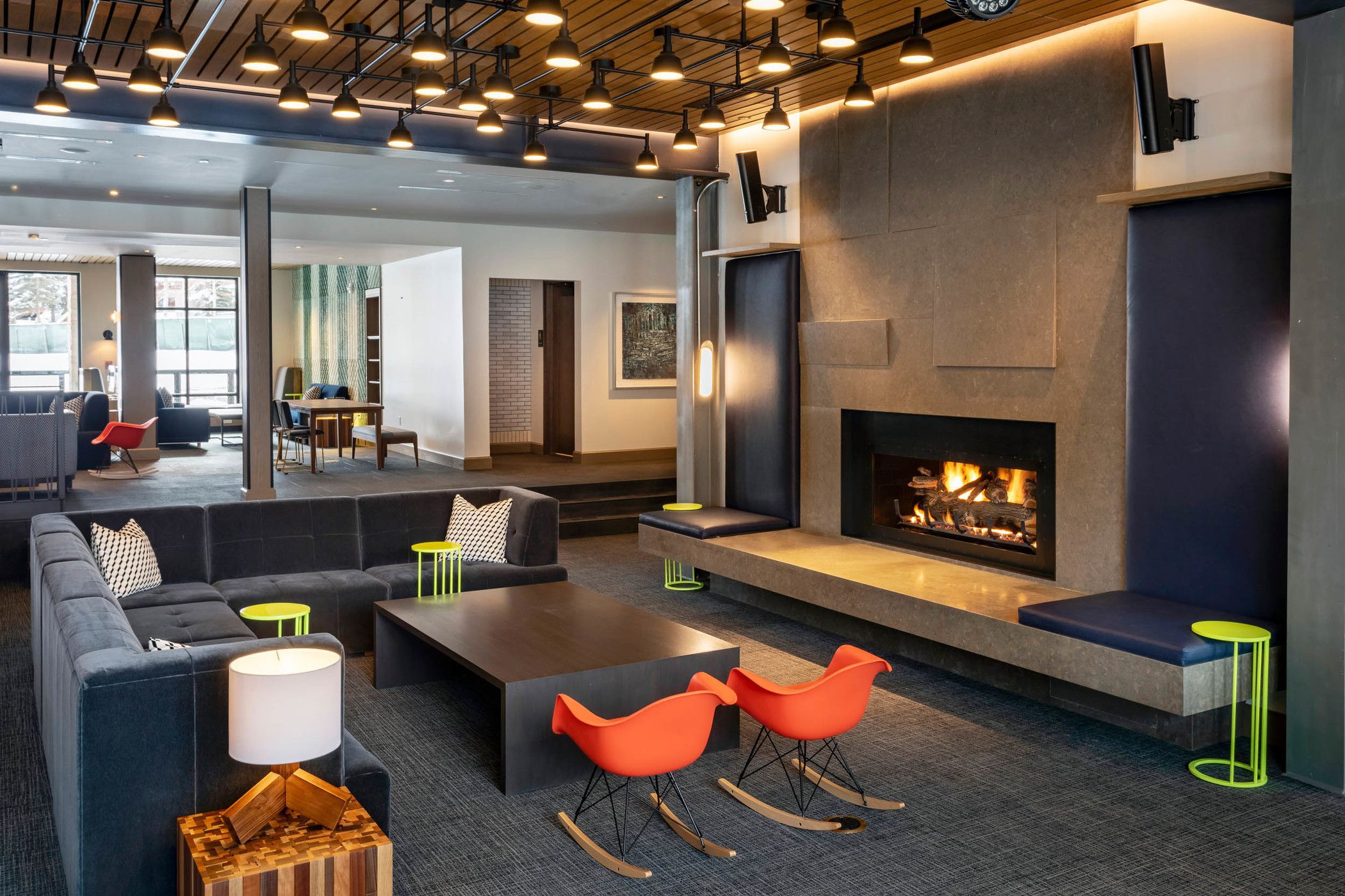 Un área de descanso moderna con chimenea, asientos y una iluminación ambiental.